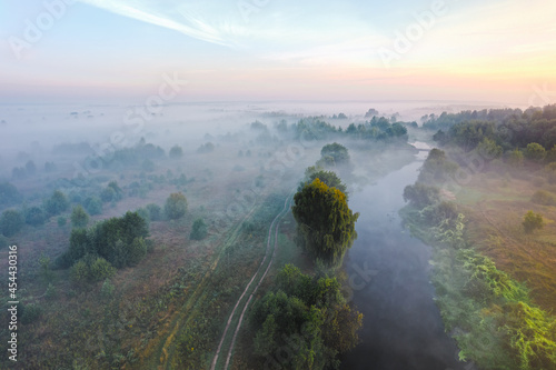 Aerial panoramic view of misty countryside in the summer morning hour with river, meadows, trees. photo