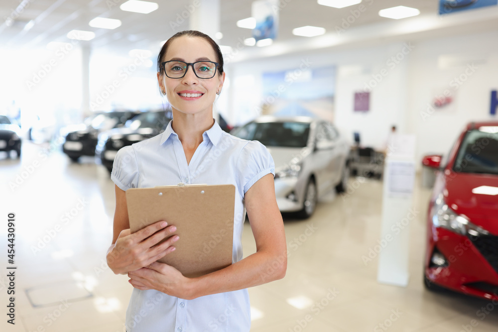 Fototapeta premium Woman manager consultant stands in car showroom closeup