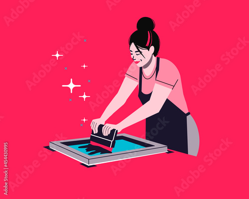 Screen printing artist. silkscreen printing technique. female printmaker using traditional printmaking method to transfer ink to paper and textile using squeegee.