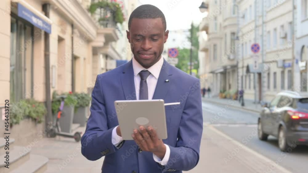 African Businessman Working on Tablet while Walking on Street African Businessman Working on Tablet while Walking on Street
