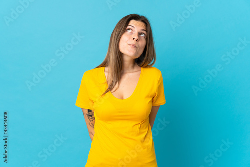 Young slovak woman isolated on blue background and looking up