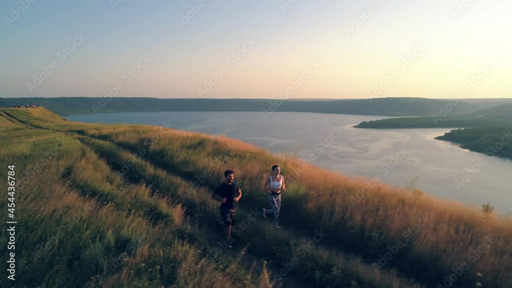The man and woman jogging on the beautiful river background. slow motion The man and woman jogging on the beautiful river background. slow motion