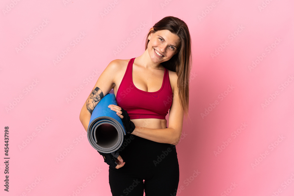 Obraz premium Young slovak woman isolated on pink background with a mat and smiling