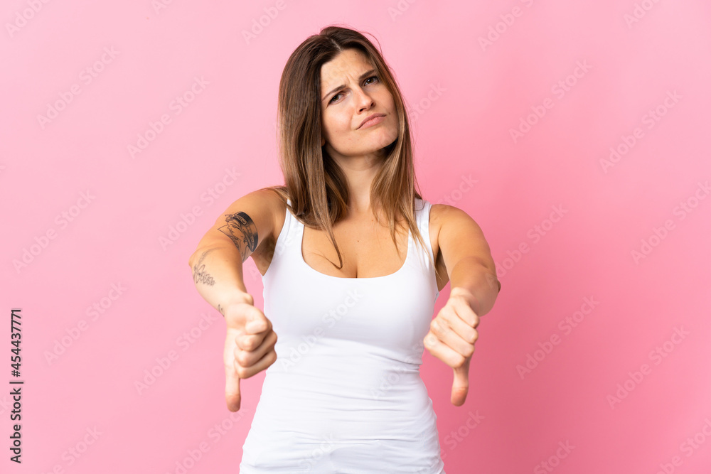 Young slovak woman isolated on pink background showing thumb down with two hands