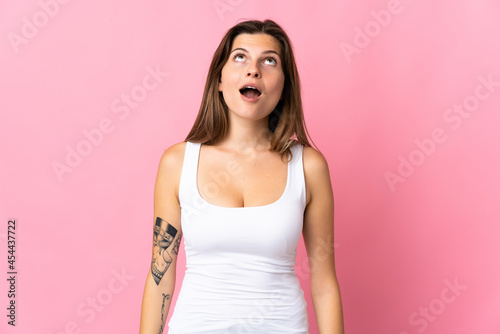 Young slovak woman isolated on pink background looking up and with surprised expression