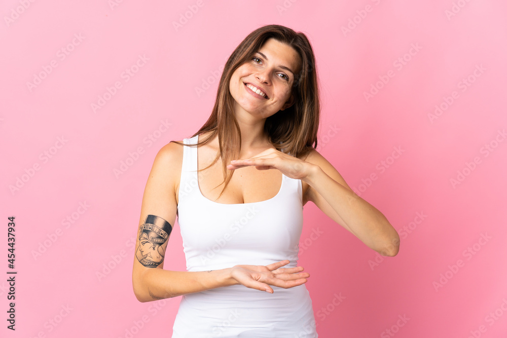 Young slovak woman isolated on pink background holding copyspace imaginary on the palm to insert an ad Young slovak woman isolated on pink background holding copyspace imaginary on the palm to insert an ad