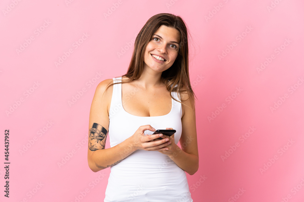 Young slovak woman isolated on pink background sending a message with the mobile Young slovak woman isolated on pink background sending a message with the mobile