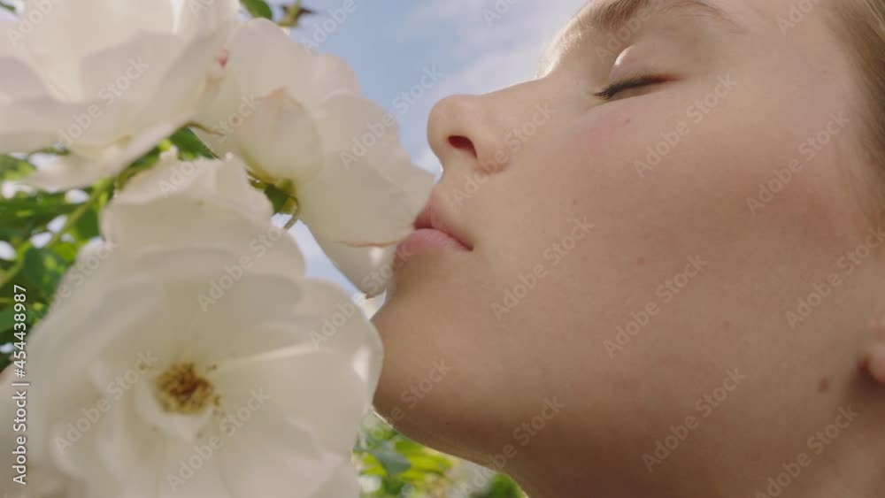 close up beautiful woman smelling roses blossoming in rose garden enjoying natural scent 