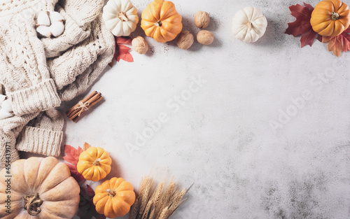 Autumn composition. Pumpkin, cotton flowers, autumn leaves and sweater on stone background. Flat lay, top view with copy space.