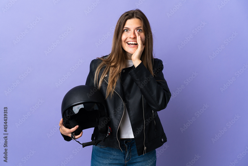 Young slovak woman holding a motorcycle helmet isolated on purple background shouting with mouth wide open Young slovak woman holding a motorcycle helmet isolated on purple background shouting with mouth wide open