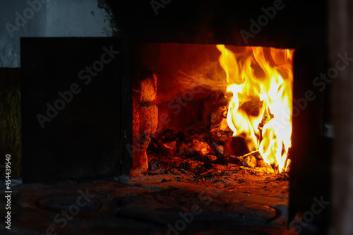 Defocus fire flame background. Firewood burning in old stove or oven. Dark and black. Orange flame. Heat energy. Open iron door. Rustic house. Blazing abstract. Out of focus