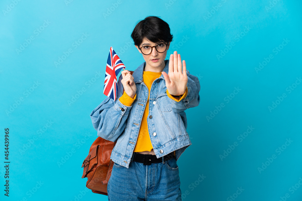 Woman holding an United Kingdom flag over isolated background making stop gesture Woman holding an United Kingdom flag over isolated background making stop gesture