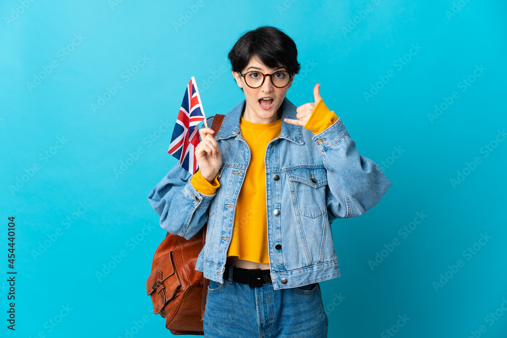 Woman holding an United Kingdom flag over isolated background making phone gesture. Call me back sign Woman holding an United Kingdom flag over isolated background making phone gesture. Call me back sign