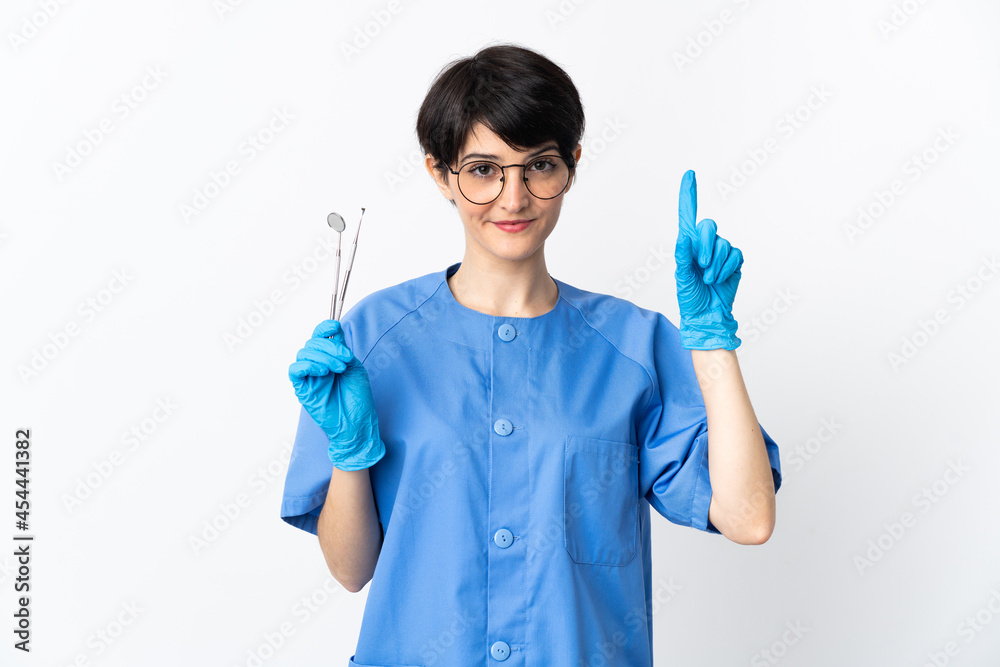 Dentist woman holding tools isolated on white background pointing up a great idea Dentist woman holding tools isolated on white background pointing up a great idea