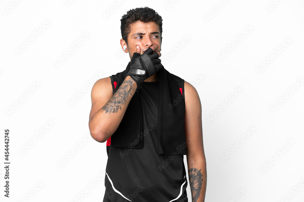 Sport brazilian man with towel isolated on white background having doubts and with confuse face expression Sport brazilian man with towel isolated on white background having doubts and with confuse face expression