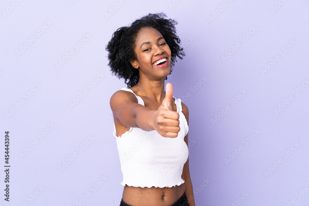 Young African American woman isolated on purple background with thumbs up because something good has happened Young African American woman isolated on purple background with thumbs up because something good has happened