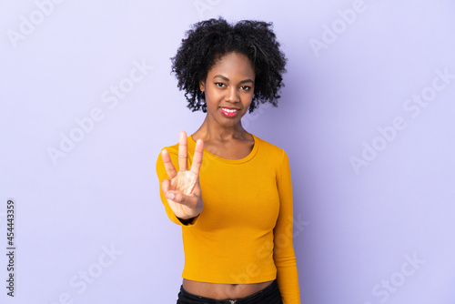 Young African American woman isolated on purple background happy and counting three with fingers
