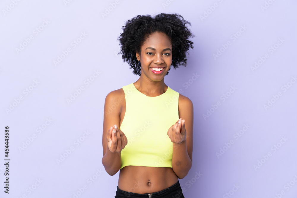 Young African American woman isolated on purple background making money gesture