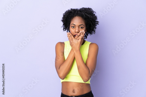 Young African American woman isolated on purple background covering mouth with hands