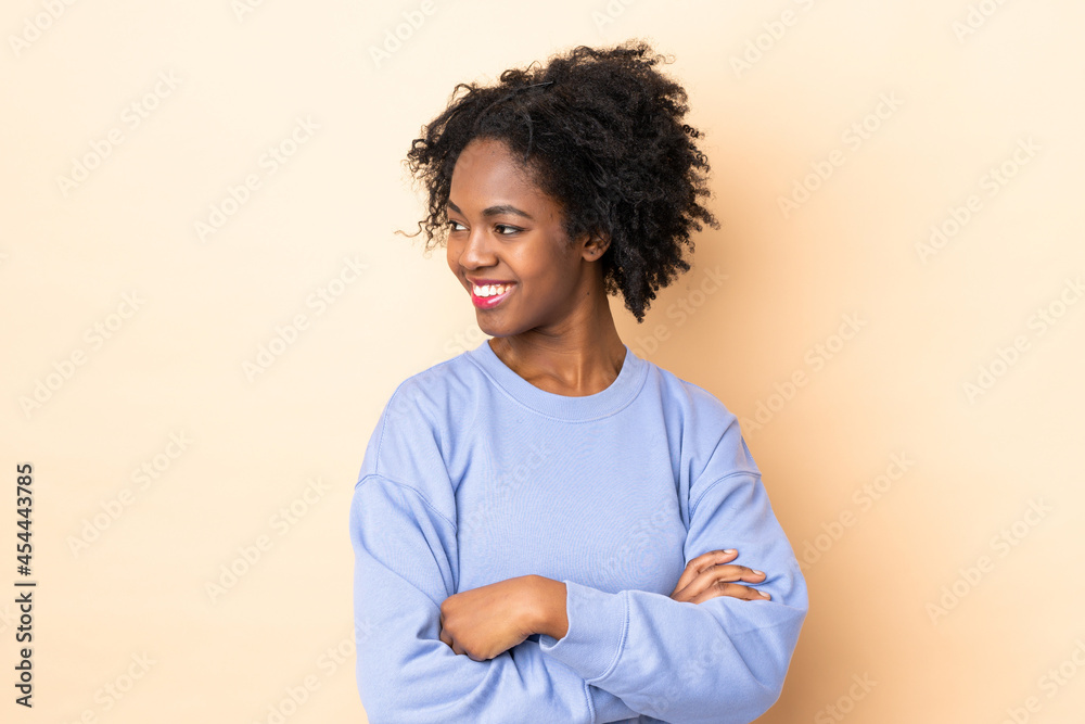 Young African American woman isolated on beige background looking side