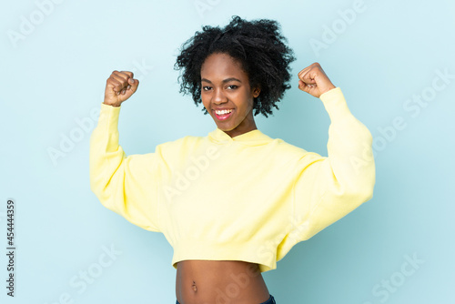 Young African American woman isolated on blue background doing strong gesture