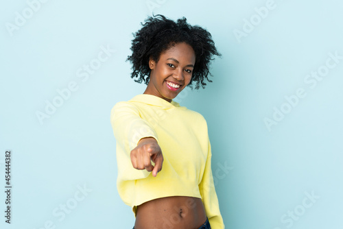 Young African American woman isolated on blue background pointing front with happy expression
