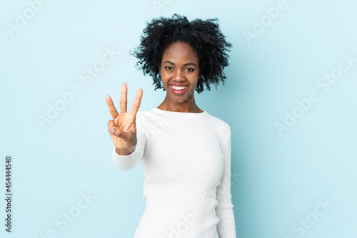 Young African American woman isolated on blue background happy and counting three with fingers