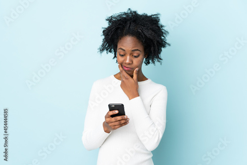 Young African American woman isolated on blue background thinking and sending a message