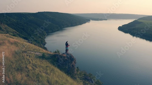 The man and woman standing on rocky mountain edge against the river
