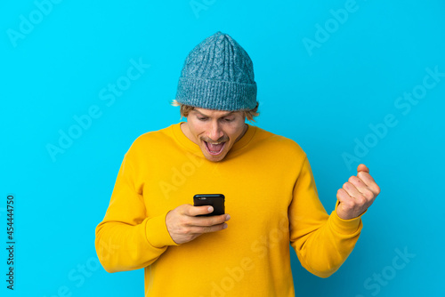 Handsome blonde man isolated on blue background surprised and sending a message © luismolinero