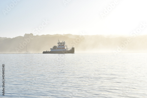 Backlit tugboat in a summer morning fog.  Copy space.  Long Island, New York. photo