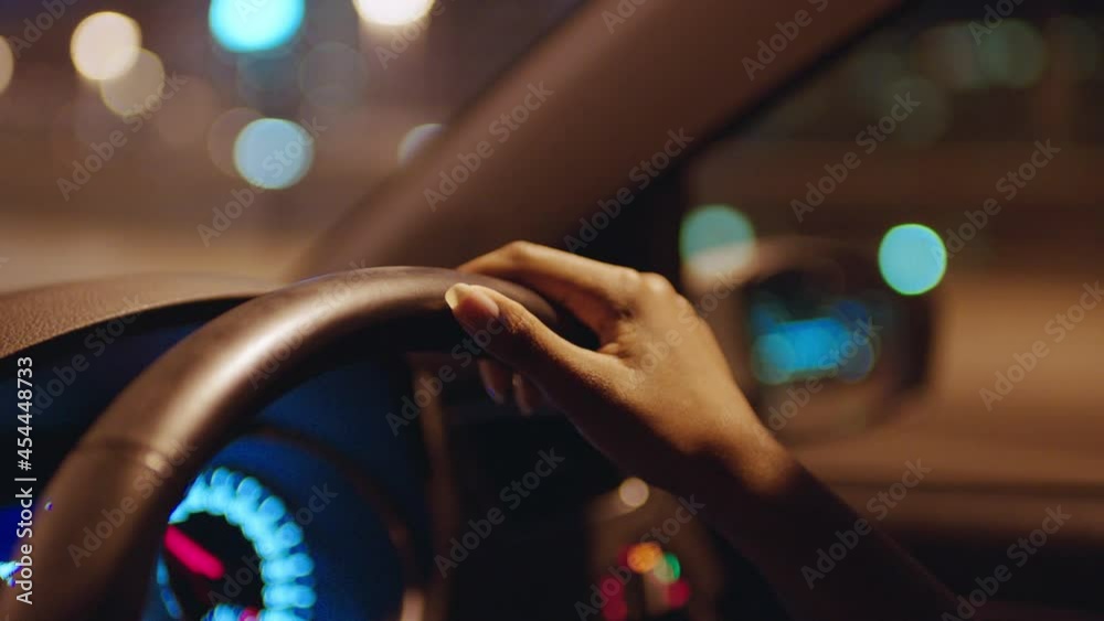 woman driving car with hands on steering wheel in city at night travelling on the road to destination 