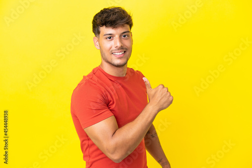 Young caucasian handsome man isolated on yellow background proud and self-satisfied