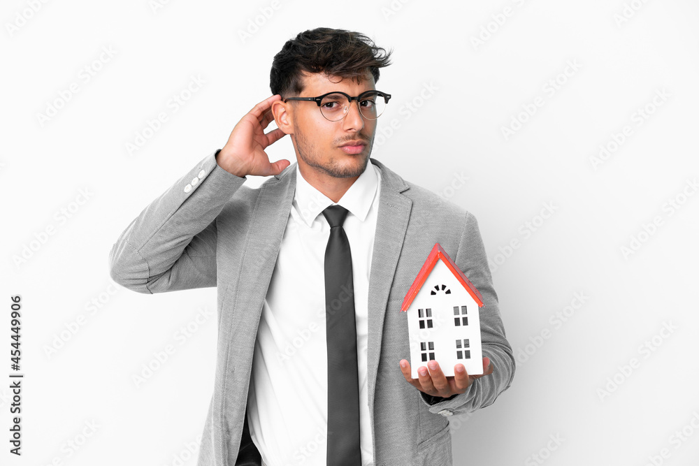 Business man holding a house isolated on blue background having doubts