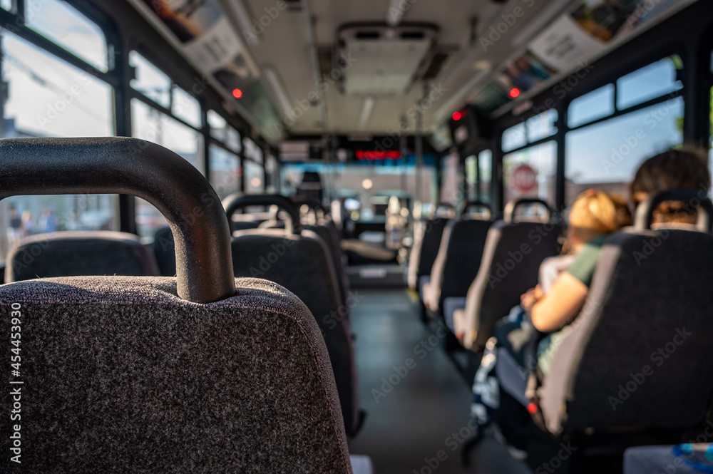 Focus on an empty seat in a bus with only a single mother and child in the distance. Focus on an empty seat in a bus with only a single mother and child in the distance.