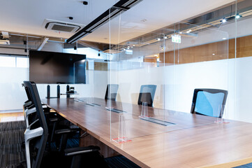 Television blank display in video conference meeting room with clear acrylic sheet separates the center on the conference table to prevent Covid-19