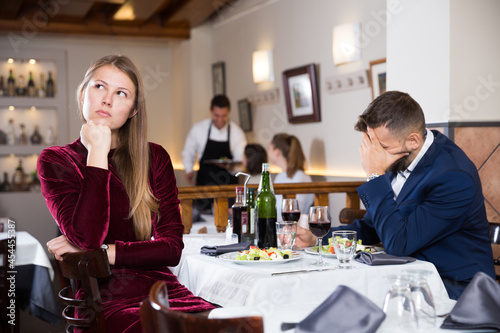 Depressed couple sitting at restaurant unhappy after quarrel on date