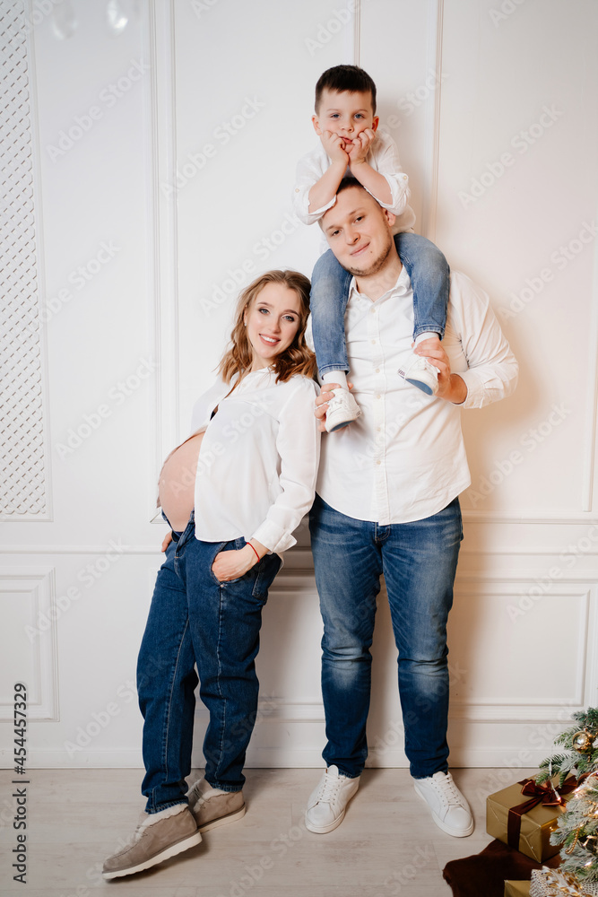 happy family. pregnant mother with her son and father in jeans and a white shirt happy family. pregnant mother with her son and father in jeans and a white shirt