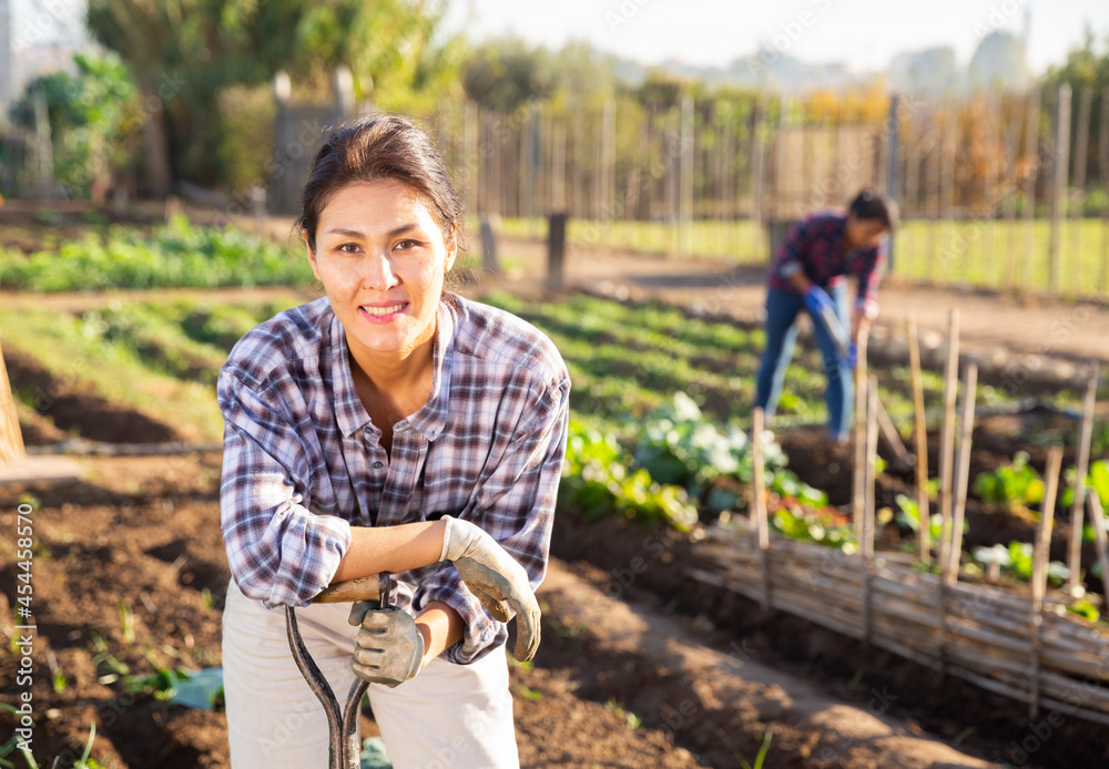 Portrait of positive female gardener posing in backyard garden on sunny ...