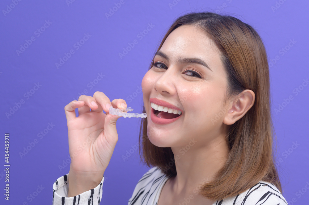 Young smiling woman holding invisalign braces in studio, dental healthcare and Orthodontic concept.. Young smiling woman holding invisalign braces in studio, dental healthcare and Orthodontic concept..