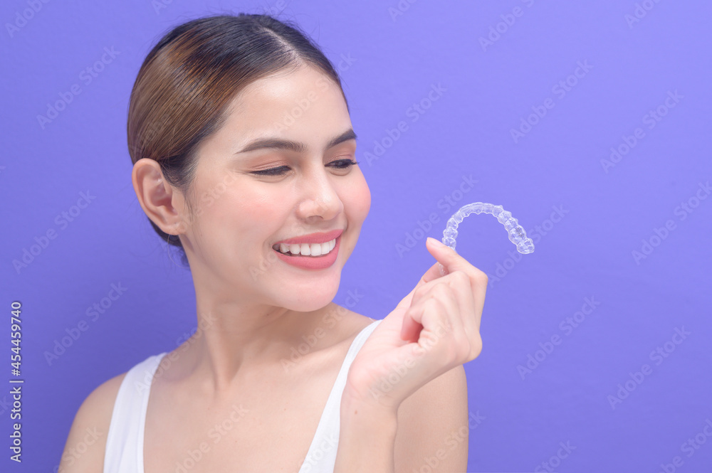 Young smiling woman holding invisalign braces in studio, dental healthcare and Orthodontic concept.. Young smiling woman holding invisalign braces in studio, dental healthcare and Orthodontic concept..