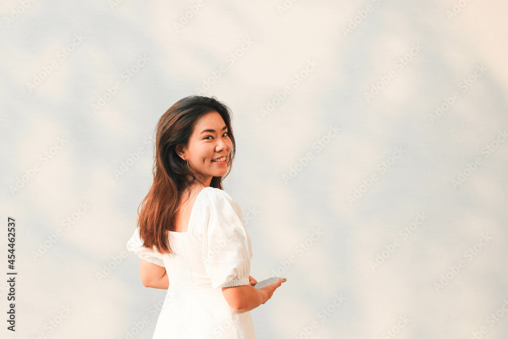 Naklejka premium Beautiful Asian woman turn back and smile to camera with white wall background.