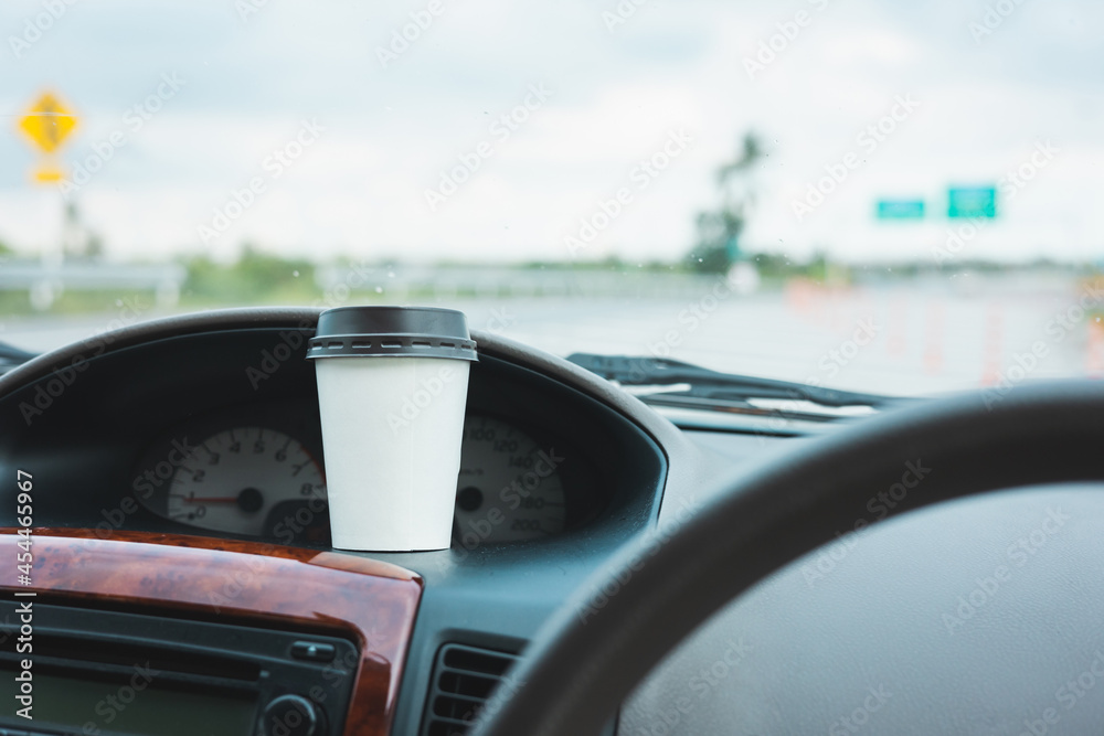 A cup of hot coffee put on the car console. Drinking coffee while travel by car. A cup of hot coffee put on the car console. Drinking coffee while travel by car.