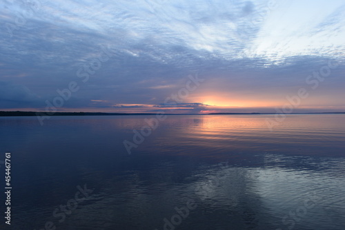 Sunset glow in the clouds on the horizon on the horizon over calm water