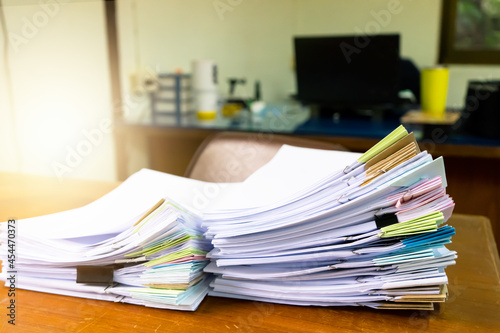 Pile of unfinished documents on office desk.