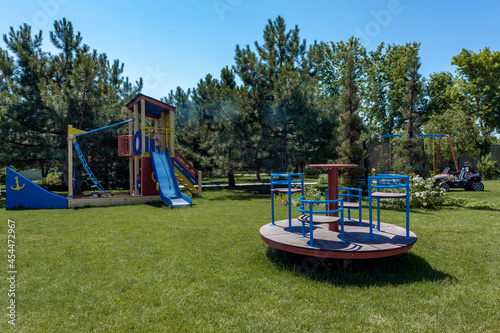 Children boat shaped play complex with slide and carousel on green lawn in summer