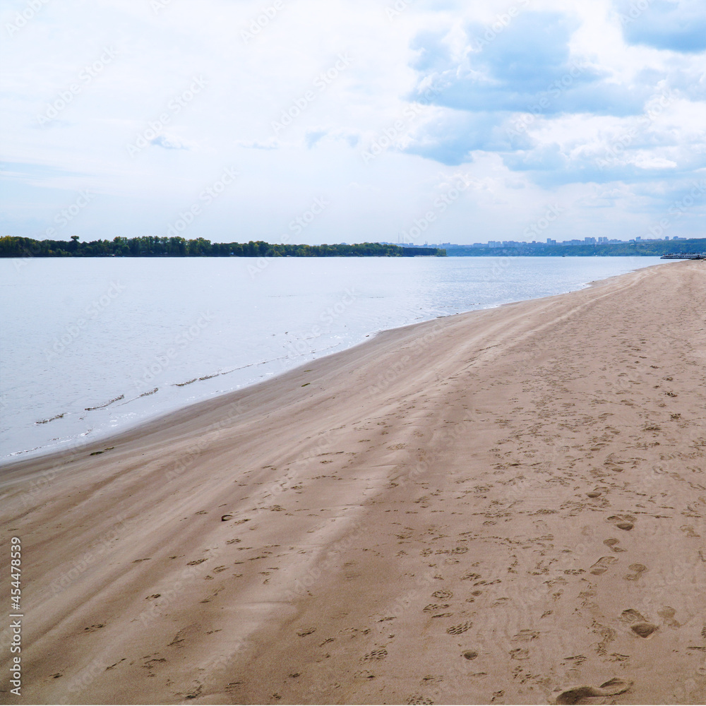 Obraz premium The sandy shore of the big Volga river against the background of a cloudy sky
