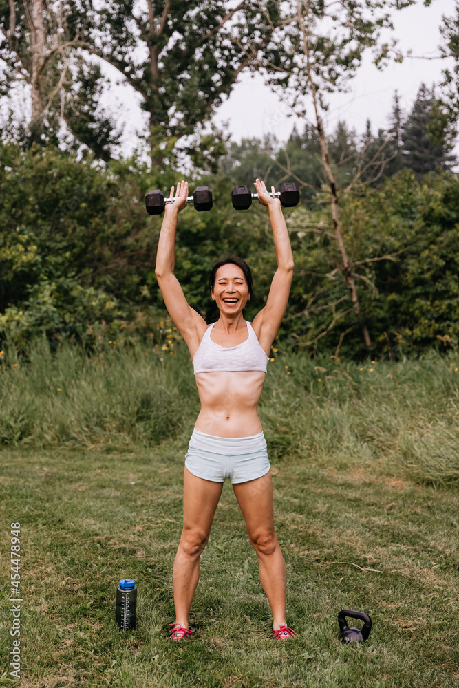 Asian woman stretching outside, after having worked out Asian woman stretching outside, after having worked out