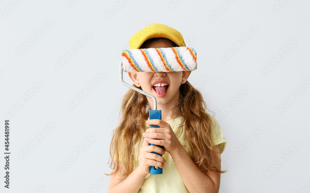 Little girl with paint roller on light background Little girl with paint roller on light background