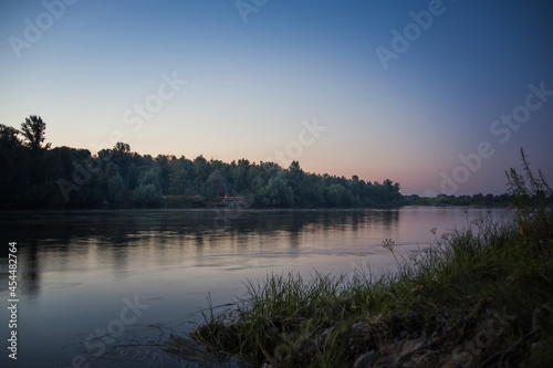 Forest and river at sunset. Deep blue-red sky at sunset near a c